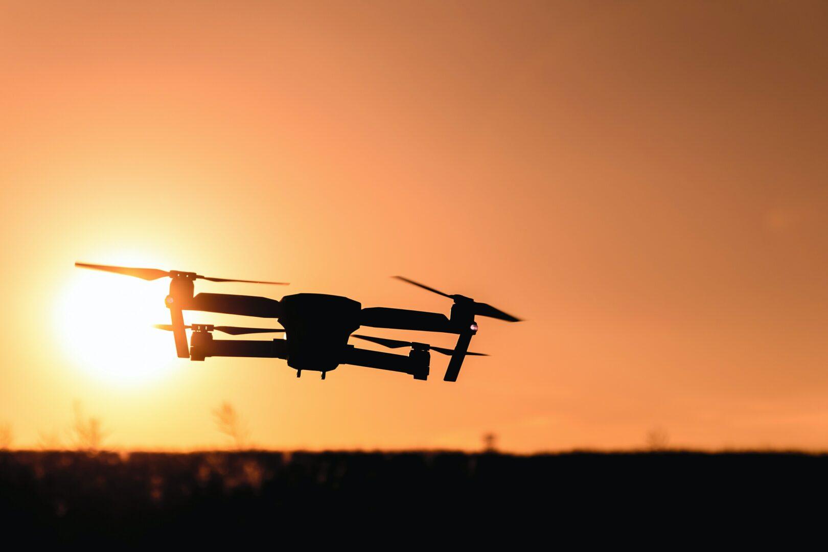 Newsletter article it's up to the drones showing a drone flying outisde at sunset